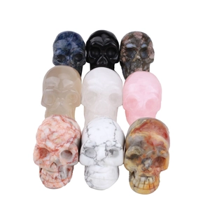 Set of nine natural gemstone skull carvings in various crystals on white background