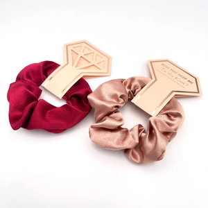 Detail of satin hair scrunchies in wine red and rose gold with diamond ring cards