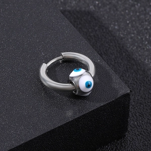 Close-up of a silver stainless steel hoop earring with a blue evil eye bead detail