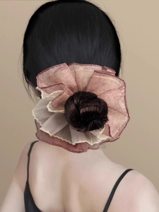 Detail of a large dusty pink chiffon flower scrunchie on a bun hairstyle