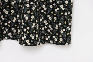 Close-up of floral print chiffon hem with white flowers on a black fabric base