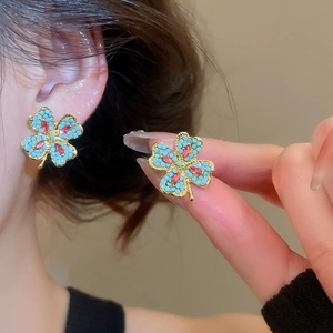 Macro shot of clover earrings with blue turquoise beads and red ruby-like zircons