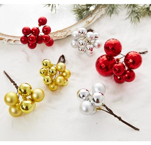 Close-up of red and gold Christmas berry clusters with matte and glossy finishes on snow