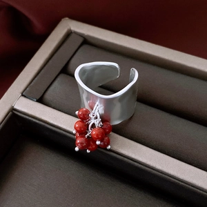 Detailed close-up of wide hammered silver ring with vibrant red bead cluster pendant