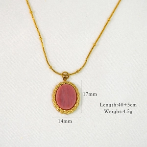 Macro detail of gold necklace with pink oval stone pendant and technical dimensions