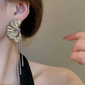 Macro shot of silver tassel earrings with fan-shaped design worn by a female model
