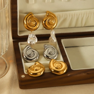 Detailed close-up of three pairs of conch shell earrings with baroque pearls in a wooden box