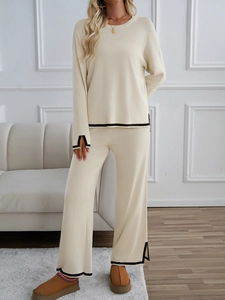 Detail of beige knit set featuring elegant black contrast piping on sleeves and wide-leg trousers