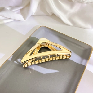 Detailansicht einer goldenen dreieckigen Haarklammer auf einem luxuriösen Tablett