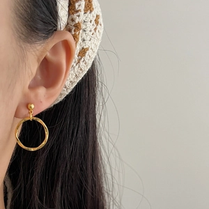 French style gold round hoop earrings with rippled texture shown on ear for women