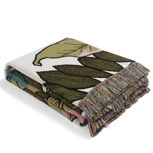 Detail of woven camping blanket showing green leaf patterns and colorful fringe edges