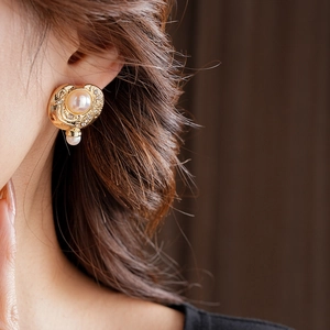 Gros plan de boucles d'oreilles vintage en perles dorées avec détails en diamant sur modèle