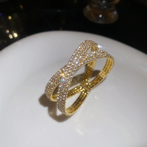 Gros plan sur le design croisé pavé de ce luxueux bracelet doré orné de strass