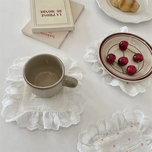 Detailed close-up of white lace square and round coasters with pink heart embroidery