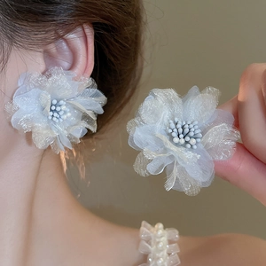 Detailed view of layered organza flower earrings with pearl centers on female model