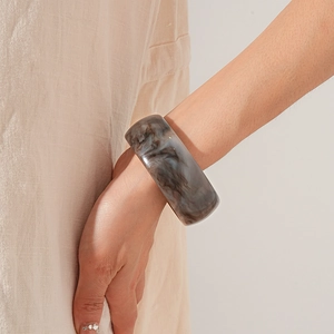 Detailed view of wide resin bangle with grey and white marble texture on a model wrist