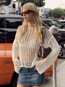 Outdoor street style shot of a woman in white crochet knit top and denim mini skirt