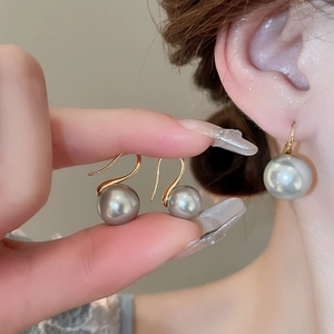 Macro shot of 10mm grey pearl drop earrings with 18K gold hooks shown on ear