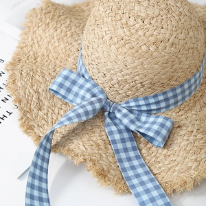 Wide brim raffia sun hat with blue gingham ribbon and frayed edges for beach vacation