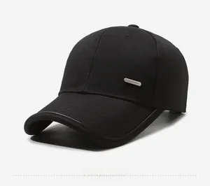 Detail of a minimalist black baseball cap featuring a metal logo plate on twill cotton fabric