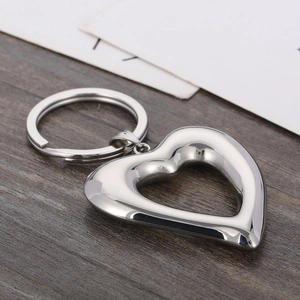 Close-up of polished stainless steel hollow heart-shaped keychain on wooden background