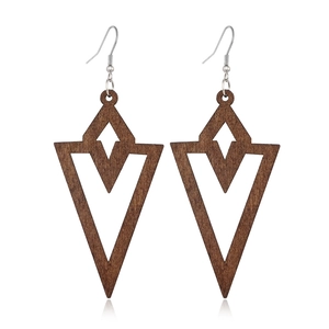 Close-up of geometric hollow wood earrings with brown arrow and diamond patterns
