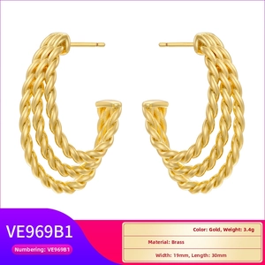 Detailed macro view of gold-plated brass C-shaped hoop earrings with twisted texture