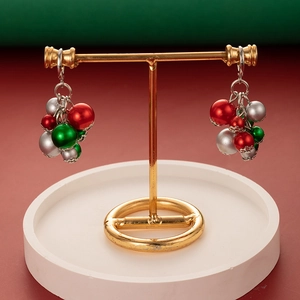 Close-up of Christmas ball drop earrings in red green and silver on a golden display stand