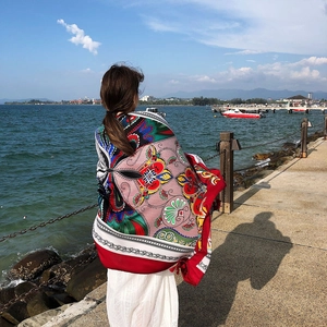 Close-up of lightweight red ethnic pattern beach shawl with sea and blue sky backdrop