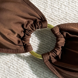 Gros plan du tissu de bikini marron chocolat avec anneau métallique doré