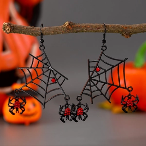 Detail of Halloween spider web earrings with red rhinestones hanging on a dry branch