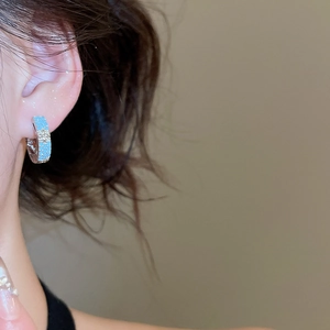 Detail of silver hoop earring with blue shimmering finish and hexagonal star design