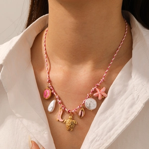 Detail of pink braided rope necklace with golden charms like starfish and sea turtle