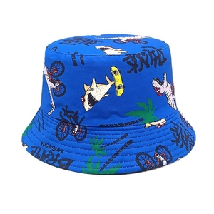 Close-up of blue sun hat fabric with shark, dinosaur and skateboard cartoon prints