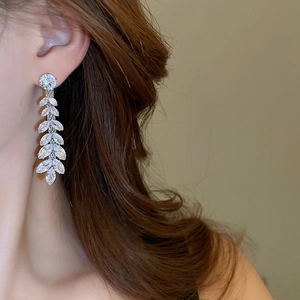 Detail view of silver tassel earrings with zircon wheat ears on a professional model