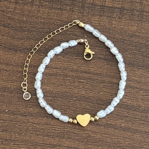 Dettaglio di perle barocche irregolari e ciondolo a cuore su bracciale elegante