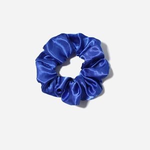 Macro shot of royal blue satin scrunchie showing silky texture and pleated fabric detail