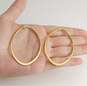 Detailed view of large gold-plated stainless steel hoop earrings held in palm for scale