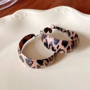 Macro shot of brown leopard print hoop earrings on a cream ceramic decorative tray