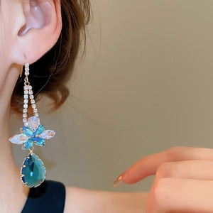 Close-up of blue water drop pendant earrings with floral zircon detailing on model