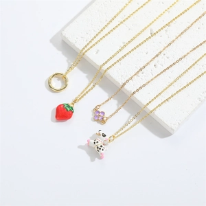 Minimalist gold necklaces with strawberry, puppy, and floral pendants on white stone