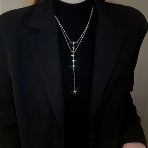 Detail of layered stainless steel star tassel necklace worn over a black blazer