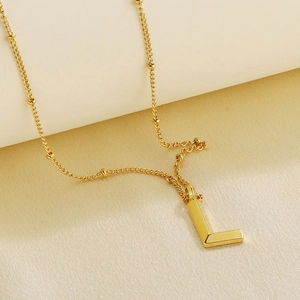 Detailed close-up of a 18k gold-plated letter L pendant with beaded chain necklace