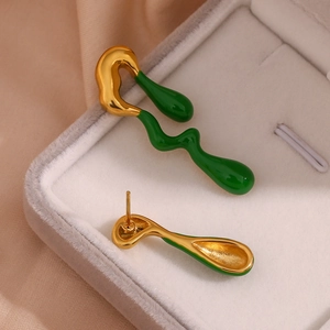 Macro detail of asymmetric gold lava earrings with dark green enamel finish