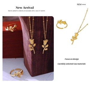Detail of elegant gold rose pendant necklace and adjustable ring set on wood base