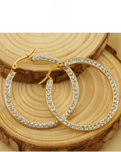 Macro detail of 18K vacuum plated gold earrings with rhinestones on a wood tray