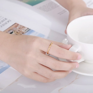 Close-up of minimalist gold twist ring worn on finger while holding a ceramic cup