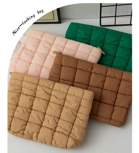 Close-up of four quilted down fabric cosmetic bags in beige, brown, pink, and green