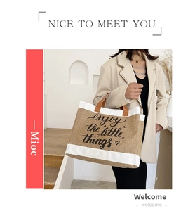 Detail of large jute tote bag with brown leather handles and printed letter design