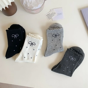 Detail of four pairs of mid-calf socks with bow embroidery and polka dots in soft tones